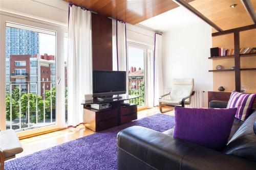 sala de estar con sofá, TV y ventanas grandes en Stay U-nique Apartments Salvador Espriu, en Barcelona