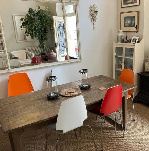 une salle à manger avec une table en bois et des chaises orange dans l'établissement Near Bergerac Airport 16th Century Town House, à Sainte-Foy-la-Grande