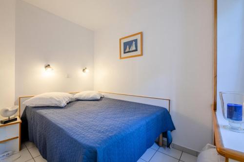 une chambre avec un lit avec une couverture bleue dans l'établissement Résidence le Hameau de Cap Esterel - maeva Home - Appartement 2 pièces 5 personnes - Sélection MAE-0051, à Saint-Raphaël
