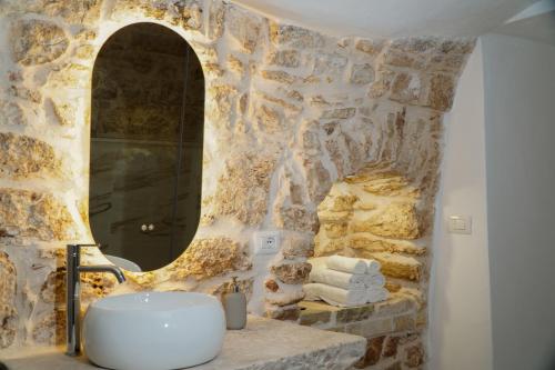 a stone bathroom with a sink and a mirror at Dimora di Sasso - Relax ed Eleganza nel Cuore della Puglia in Santeramo in Colle