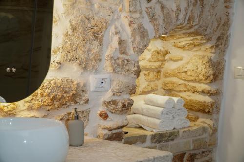 a bathroom with a pile of towels and a sink at Dimora di Sasso - Relax ed Eleganza nel Cuore della Puglia in Santeramo in Colle