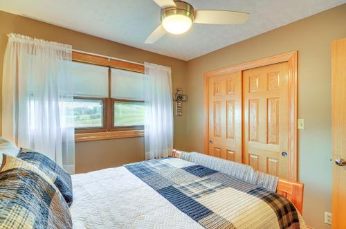 a bedroom with a bed with a ceiling fan and a window at 4 Mi to Cumberland River Cabin with Deck and Fire Pit in Burnside