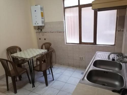 een keuken met een tafel en een wastafel en een tafel en stoelen bij Central Stay Departamentos in Oruro
