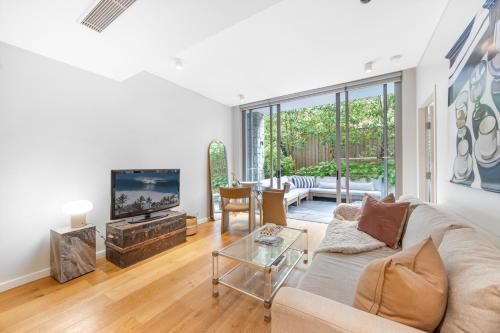 a living room with a couch and a tv at Modern & Quiet 1BR Apartment with Private Garden in Bondi close to the Beach in Sydney