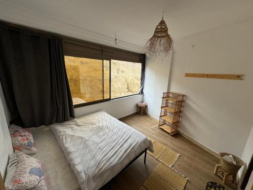 a bedroom with a bed and a large window at JUNGLE surf HOUSE in Taghazout