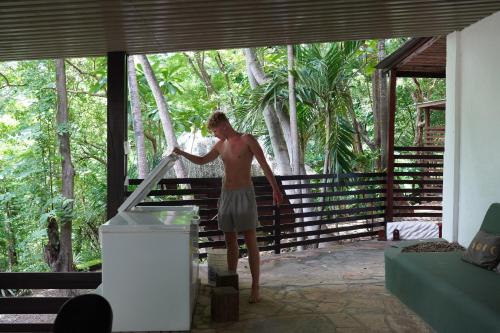 a shirtless man standing on a porch at Buena Vista Surf Club in Playa Maderas