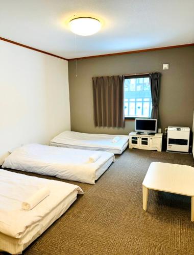 a hotel room with three beds and a television at Pension Berg in Kutchan