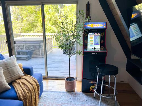 a pinball machine in a living room with a stool at Hot Tub-EV-AC-Kid Friendly-Arcade Game-Lake Access in Lake Arrowhead