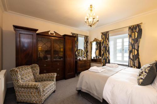 a bedroom with a bed and a chair and a chandelier at Altskeith Country House in Aberfoyle