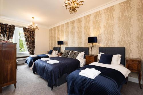 a room with four beds and a chandelier at Altskeith Country House in Aberfoyle
