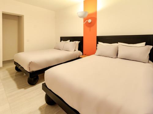 two beds in a hotel room with two beds at Roma 1888 in Guadalajara