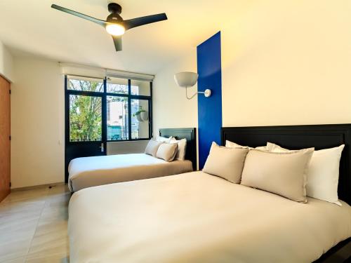 two beds in a room with a ceiling fan at Roma 1888 in Guadalajara