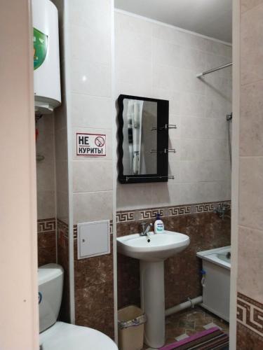 une salle de bain avec un lavabo, des toilettes et un miroir dans l'établissement Минималистичная квартира, à Kyzylorda