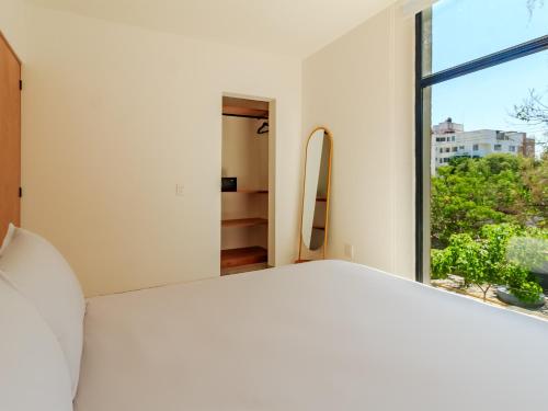 a bedroom with a large window and a bed at Roma 1888 in Guadalajara