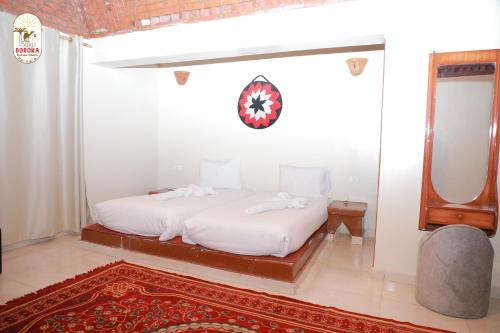 a white bedroom with a bed and a mirror at DoroKa Nubian House in Aswan