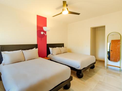 a room with two beds and a ceiling fan at Roma 1888 in Guadalajara
