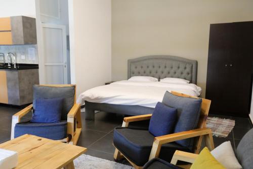朱拜勒SunnySide Apartment - Lovely and Cozy Studio in Byblos的一间卧室，里面有一张床、两把椅子和一张桌子