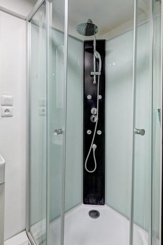 une douche dans une salle de bain avec une porte vitrée dans l'établissement Élégant studio de prestige au cœur de Paris, à Paris