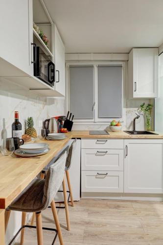 une cuisine avec des armoires blanches et un comptoir en bois dans l'établissement Élégant studio de prestige au cœur de Paris, à Paris