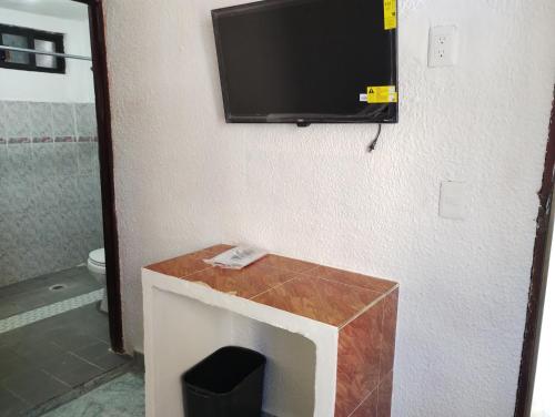 a bathroom with a tv on the wall and a toilet at Casa de huespedes LOS SANTOS in Cancún