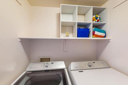 a laundry room with two washing machines and a shelf at Spearhead Serenity in Tucson
