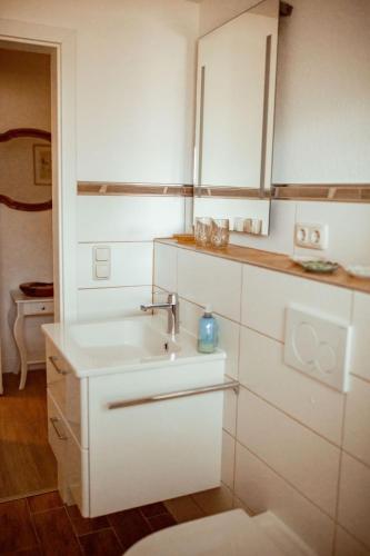 a white bathroom with a sink and a mirror at Haus Eickert - Ferienwohnung in Undeloh