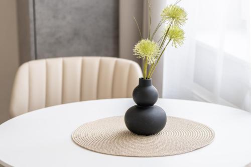a black vase sitting on a table with flowers at Apartmánový Dům Centrum in Brno