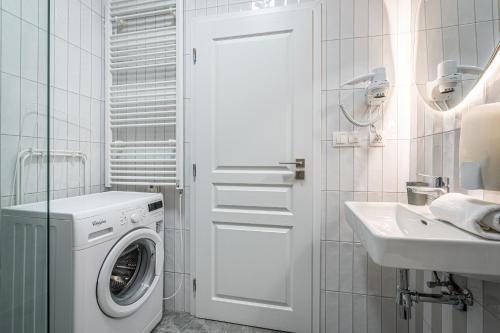 a white bathroom with a washing machine and a sink at Apartmánový Dům Centrum in Brno