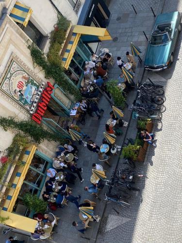 un groupe de personnes assis à des tables à l'extérieur d'un bâtiment dans l'établissement Appartement de Brigitte, à Paris