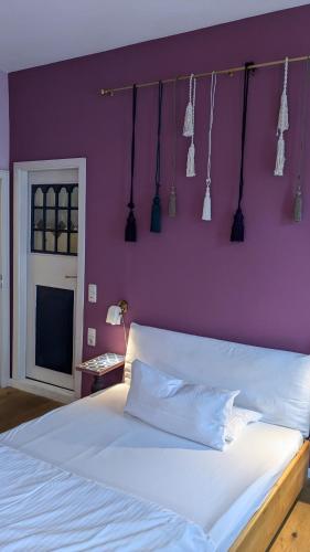 a bedroom with a white bed with a purple wall at Hotel Tafelfreuden in Oldenburg