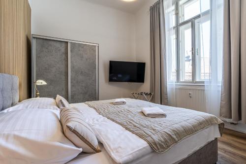 a bedroom with a large bed with a tv on the wall at Apartmánový Dům Centrum in Brno