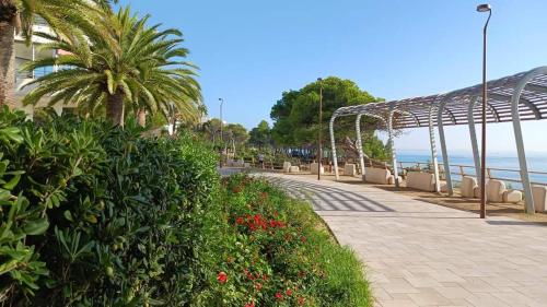a sidewalk next to the ocean with palm trees and flowers at Piso California 3 aire acondicionado, wifi, cerca del mar in Miami Platja