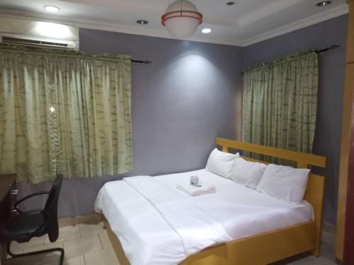 a bedroom with a large white bed with a chair at Haute Aparthotel in Ikeja