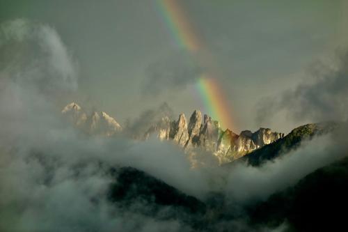 a rainbow in front of a mountain with clouds at Oberprantschöllhof - Horse Mountain Stable in Bressanone