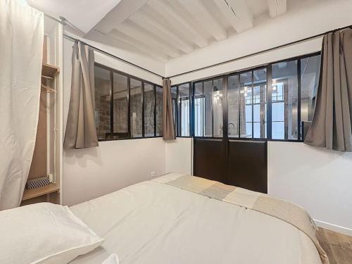 une chambre avec un grand lit blanc et des fenêtres dans l'établissement Loft en plein coeur du Marais, à Paris