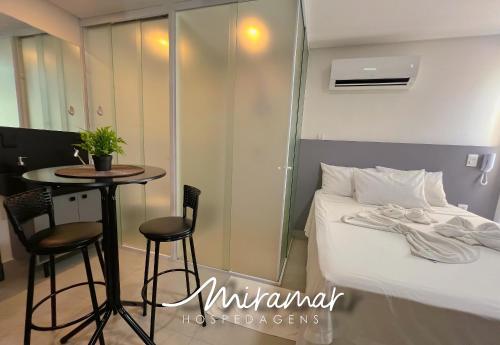 a hotel room with a bed and a table and a table at Get By Side - Jardim Oceania in Tambaú