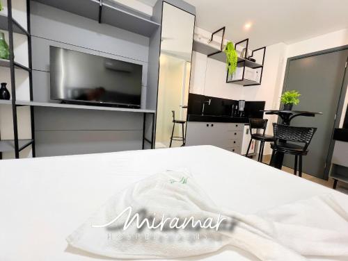 a room with a white bed and a tv at Get By Side - Jardim Oceania in Tambaú
