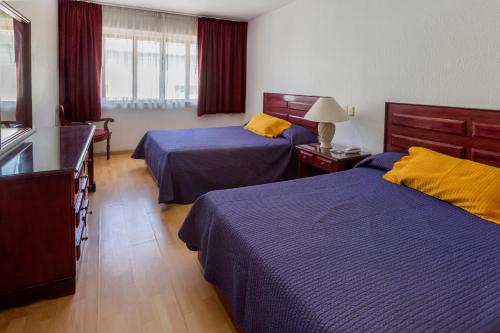 オアハカにあるHotel Gala Oaxacaのベッド2台とドレッサーがあるホテルの部屋