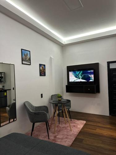 a living room with a table and a television on the wall at Casa Don José TULIPANES Suite in Oaxaca City