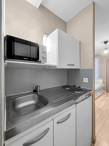 une cuisine avec un évier et un micro-ondes dans l'établissement LE Cosy De La Gare, à Tours