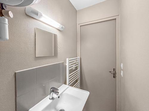 une salle de bain blanche avec un lavabo et un miroir dans l'établissement LE Cosy De La Gare, à Tours