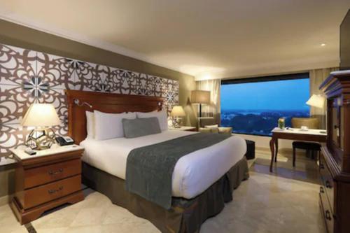 a hotel room with a bed and a desk and a window at Villahermosa Marriott Hotel in Villahermosa