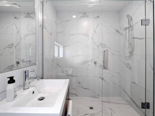 a white bathroom with a sink and a shower at Spa Hideaway in Central City with Parking in Christchurch