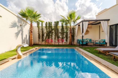 a swimming pool in a backyard with palm trees at Villa michlo in El Makina