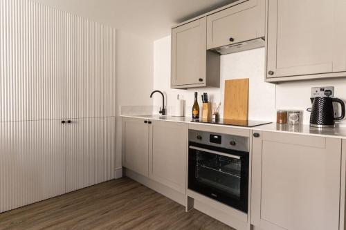 a white kitchen with white cabinets and an oven at Tiny House, Stunning 1 Bed, Super King, Freestanding Bath, Parking in Somerton