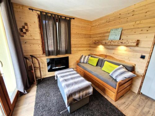 Cette cabane en rondins comprend un canapé et une cheminée. dans l'établissement Les Chalets D'arrondaz - Appartement 6/8 personnes 48 m² MAE-2903, à Modane