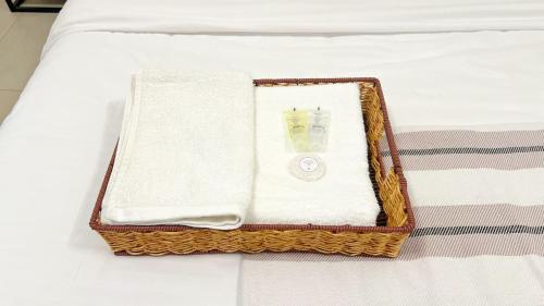 a tray with towels and a napkin on a bed at 1BHK Near Airport, Pool, Parking in Muscat