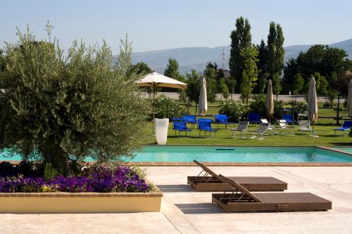 un resort con piscina, sedie e fiori di Il Baio Relais & Natural Spa a Camporoppolo