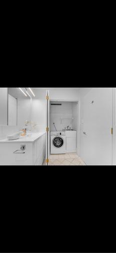 a white kitchen with a sink and a washing machine at newmarket fully furnished 2 bedrooms in Auckland