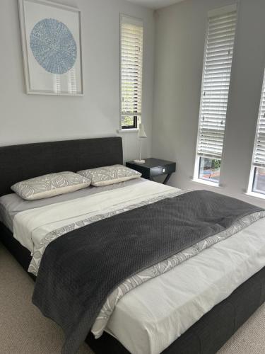 a large bed in a bedroom with two windows at newmarket fully furnished 2 bedrooms in Auckland